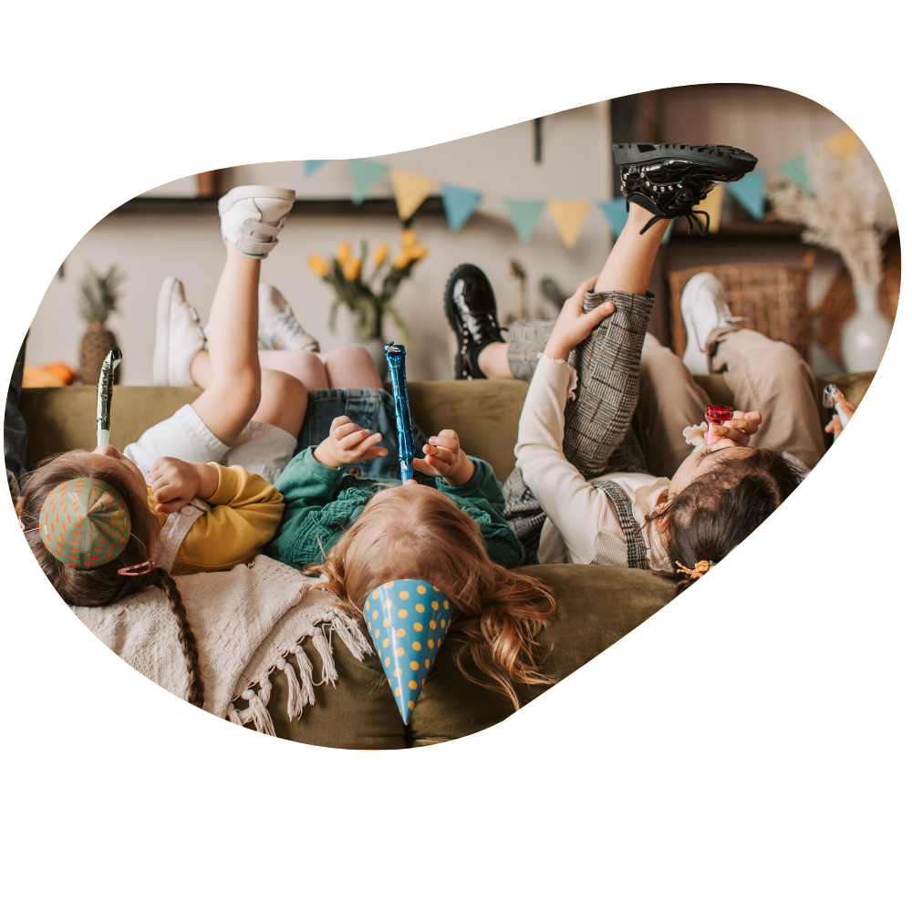 Kinder liegen auf dem Rücken auf einer Couch und haben Party-Accessoires
