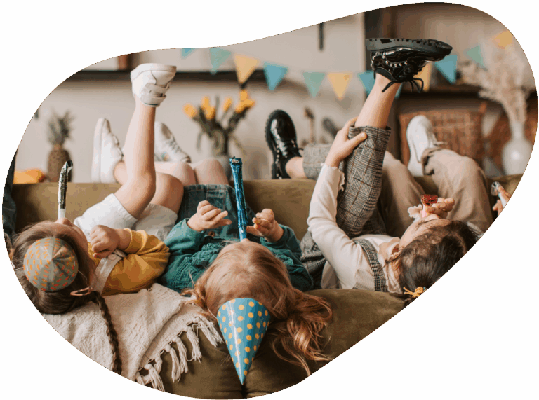 Kinder liegen auf dem Rücken auf einer Couch und haben Party-Accessoires